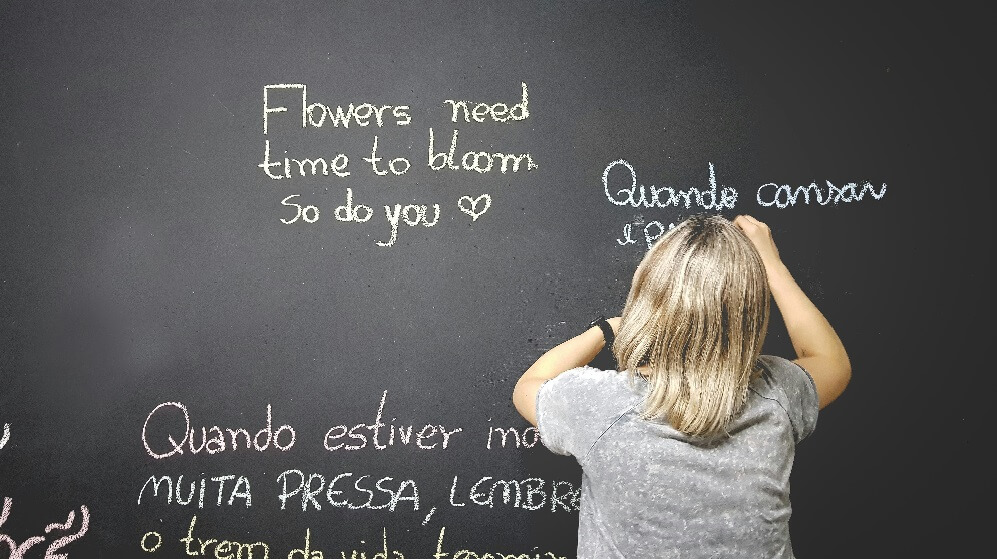 A blackboard with writing in different languages written on it in white chalk