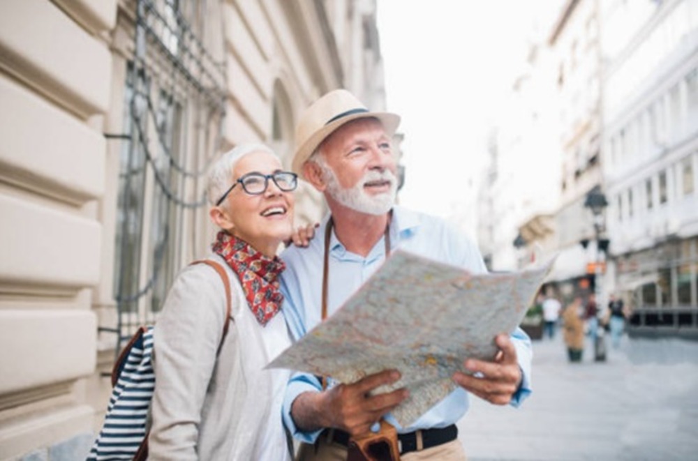 Two older tourists looking at a map in a city