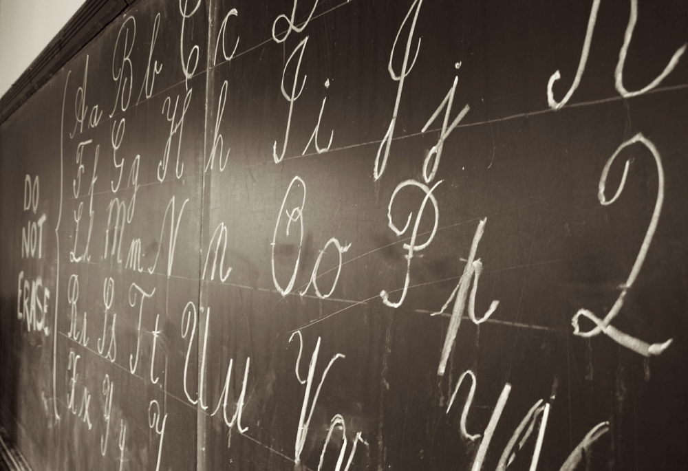 Cursive letters written in chalk on a blackboard